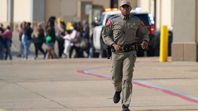 A law enforcement officer runs as people are evacuated from the mall.