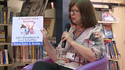 Dr Nicola Brink reads to children and answers their questions in Guernsey - she is holding up story book "A squash and a squeeze".