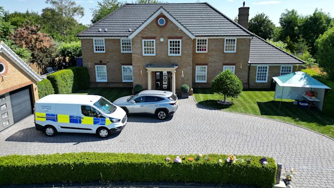 Police cars outside a large detached house