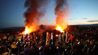 The dismantled bonfire is lit during a vigil where a man died after falling from the bonfire on the Antiville estate in Larne, Co Antrim. Picture date: Sunday July 10, 2022.