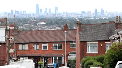 A Resident in Oldham stands in his doorway with the Manchester skyline behind, the town in Greater Manchester has seen cases of coronavirus rise in the area.