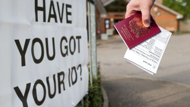 File photo dated 03/05/18 of a voter carrying his passport along with his poll card, as he makes his way to vote at The Vyne polling station in Knaphill, as ministers have reminded voters in England to check they have an accepted form of photographic identification if they plan to vote in person during next month's local elections.