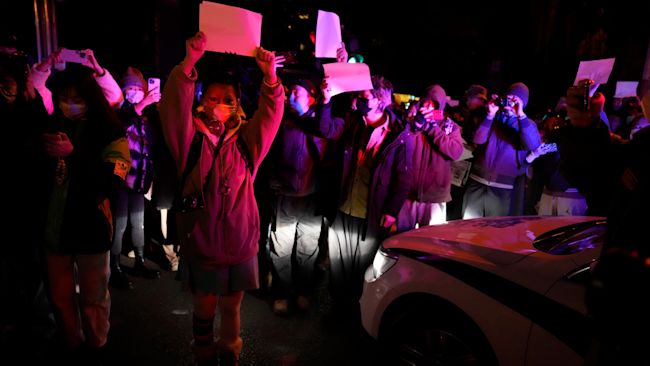 Protesters hold up blank papers and chant slogans last November