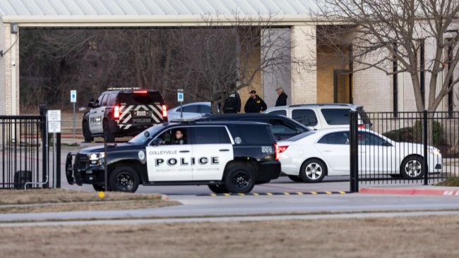 Police stand in front of the Congregation Beth Israel synagogue, Sunday, Jan. 16, 2022, in Colleyville, Texas. A man held hostages for more than 10 hours Saturday inside the temple. The hostages were able to escape and the hostage taker was killed. FBI Special Agent in Charge Matt DeSarno said a team would investigate "the shooting incident." (AP Photo/Brandon Wade)