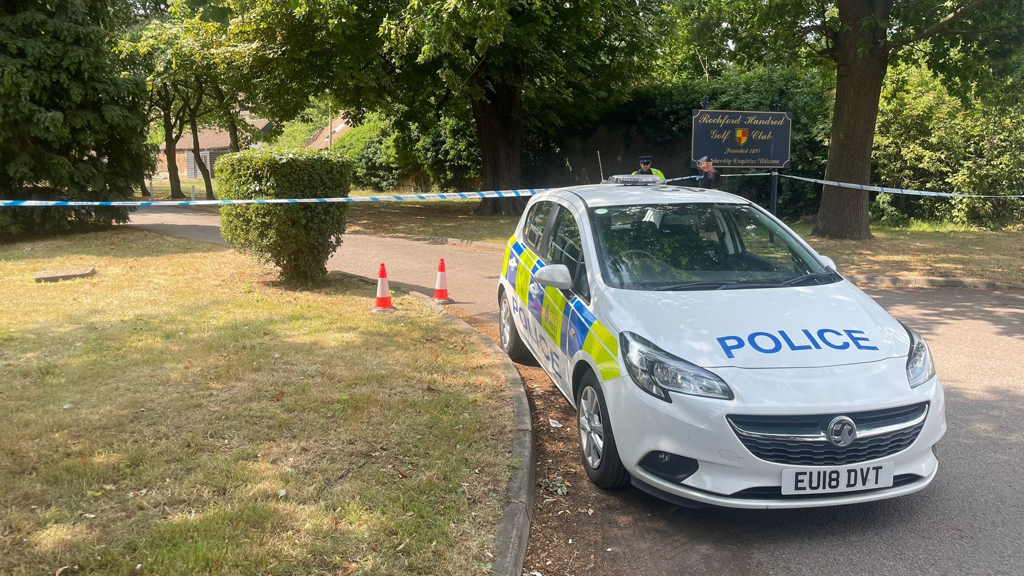 A police car in a shaded wooded area. 