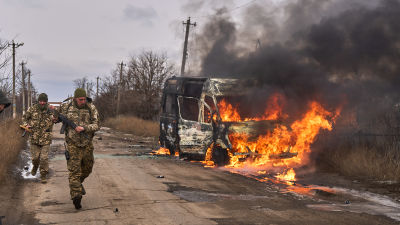 Ukrainian soldiers walk past a burning vehicle near Bakhmut, Ukraine.