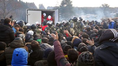 Belarusian servicemen control the situation while migrants get humanitarian aid as they gather at the Belarus-Poland border near Grodno, Belarus, Friday, Nov. 12, 2021. Thousands of people from Middle Eastern nations devastated by conflict have been trying to slip into the European Union. They are using a backdoor that was surreptitiously opened by Belarus a few months ago. (Ramil Nasibulin/BelTA pool photo via AP)