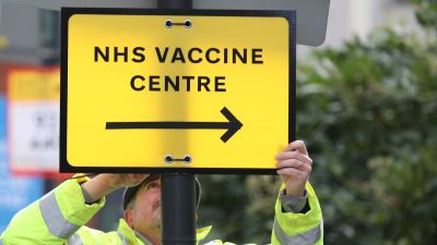 A Brent Council worker hangs a direction sign to the NHS Covid Vaccine Centre at the Olympic Office Centre, Wembley, north London, as ten further mass vaccination centres opened in England with more than a million over-80s invited to receive their coronavirus jab. Picture date: Monday January 18, 2021.

