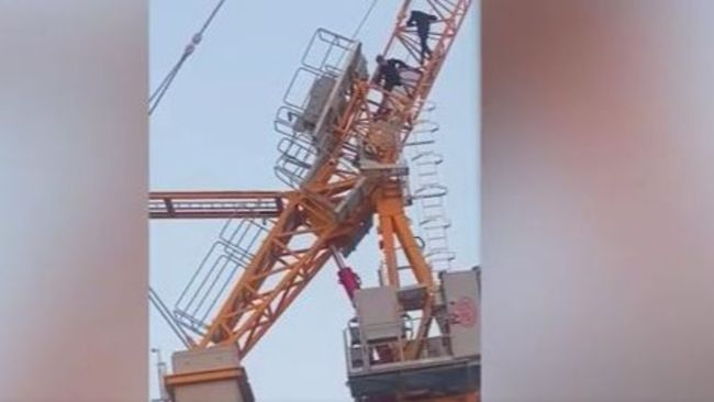 Two young people climb a crane at a Salford Housing Development.