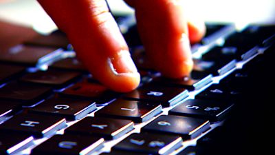 A hand typing on a computer