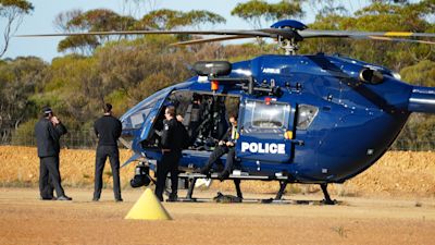 Police wait by a helicopter in Beacon, Western Australia.
