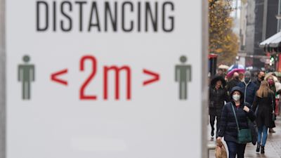 Shoppers pass social distancing signs on Oxford Street, in central London.