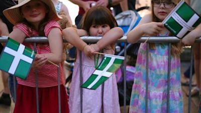 3 little girls hold devon flags in the crowd of spectators at the Tour of Britain