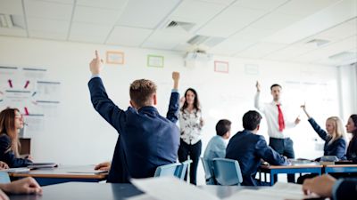 Teenage female student raising her hand to answer a question.