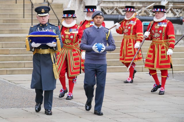 A member of the Royal Air Force Cadets (centre) holding the globe during its arrival at the Tower of London