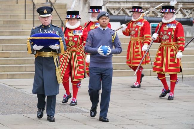 A member of the Royal Air Force Cadets (centre) holding the globe during its arrival at the Tower of London
