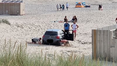 Beachgoers dig their car out of the sand in Cornwall. BPM Media/ Josh Munyard