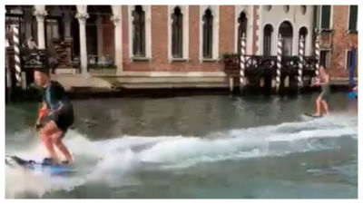 Two tourists pictured surfing down Venice's Grand Canal.