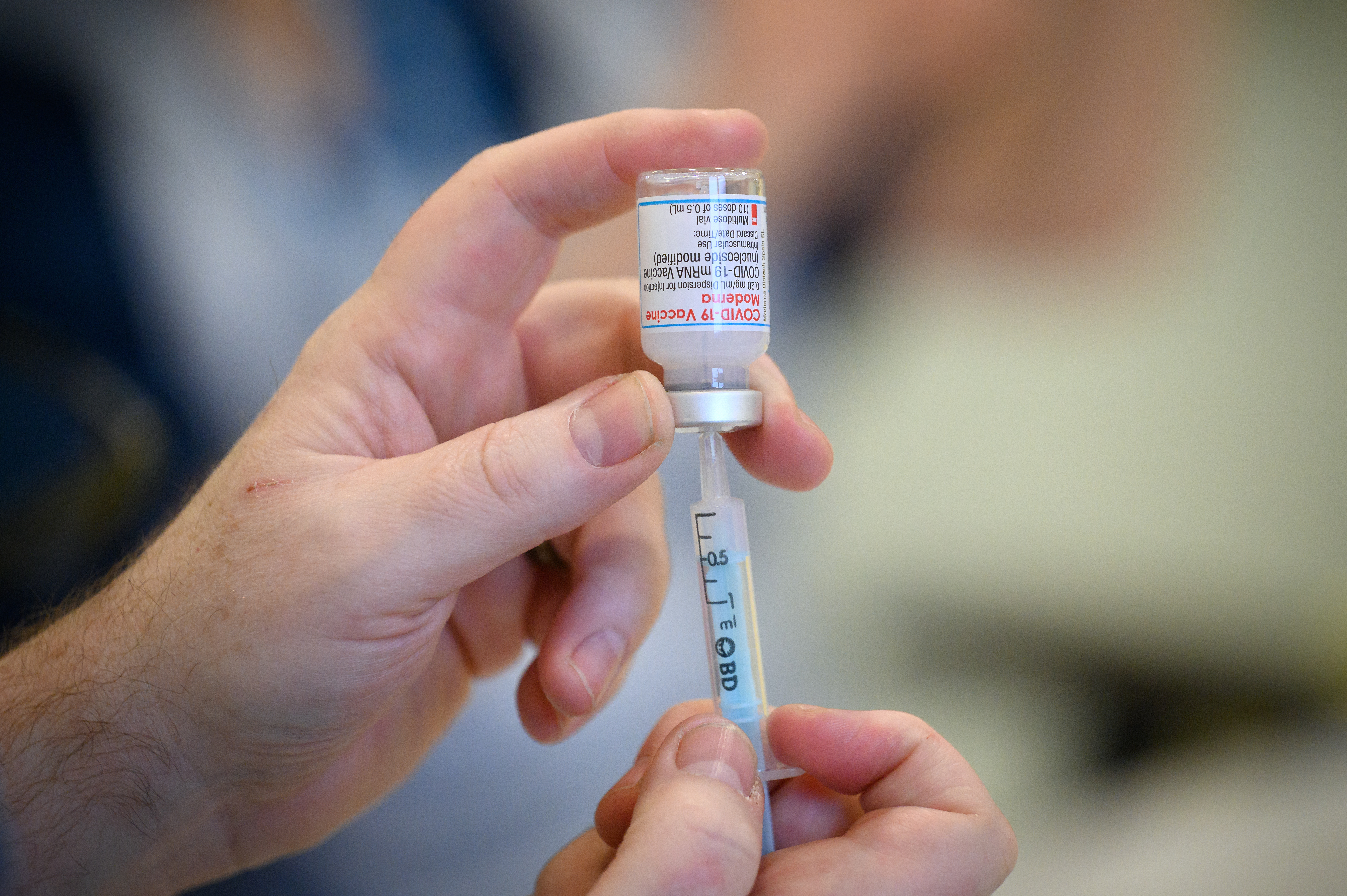 A medical professional holding a Covid vaccine bottle and needle.