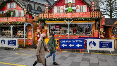 People pass Christmas market stalls in Cardiff, where restrictions across Wales have been relaxed following a two-week "firebreak" lockdown.