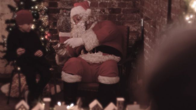 Father Christmas meeting a young boy who is neurodivergent in his adapted grotto