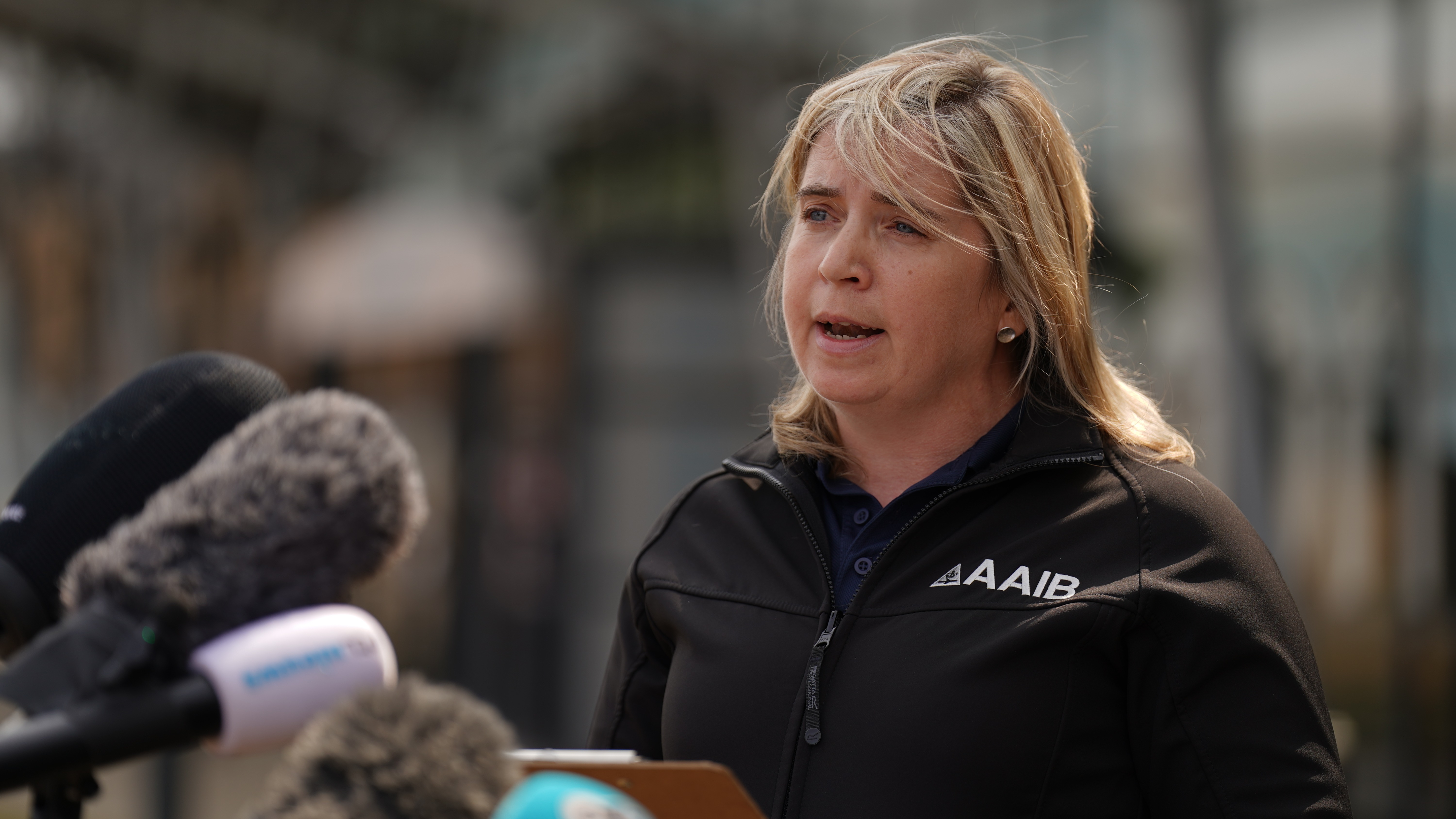 Lisa Fitzsimons wearing an AAIB fleece and speaking into microphones