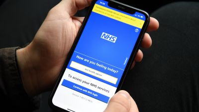A person holding a mobile phone displaying the NHS app. The NHS app will be used by holidaymakers in England to prove their coronavirus status to destination countries, Transport Secretary Grant Shapps has announced. Picture date: Wednesday April 28, 2021.

