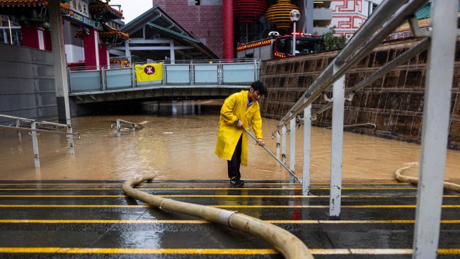 A worker clears water on a flooded street following heavy rainstorms in Hong Kong,