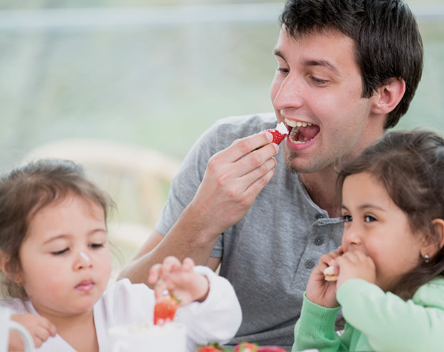 Father-and-daughters-eating-fruit