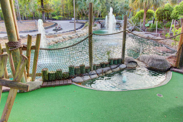 Miniature golf with fountains and go-karts in the background