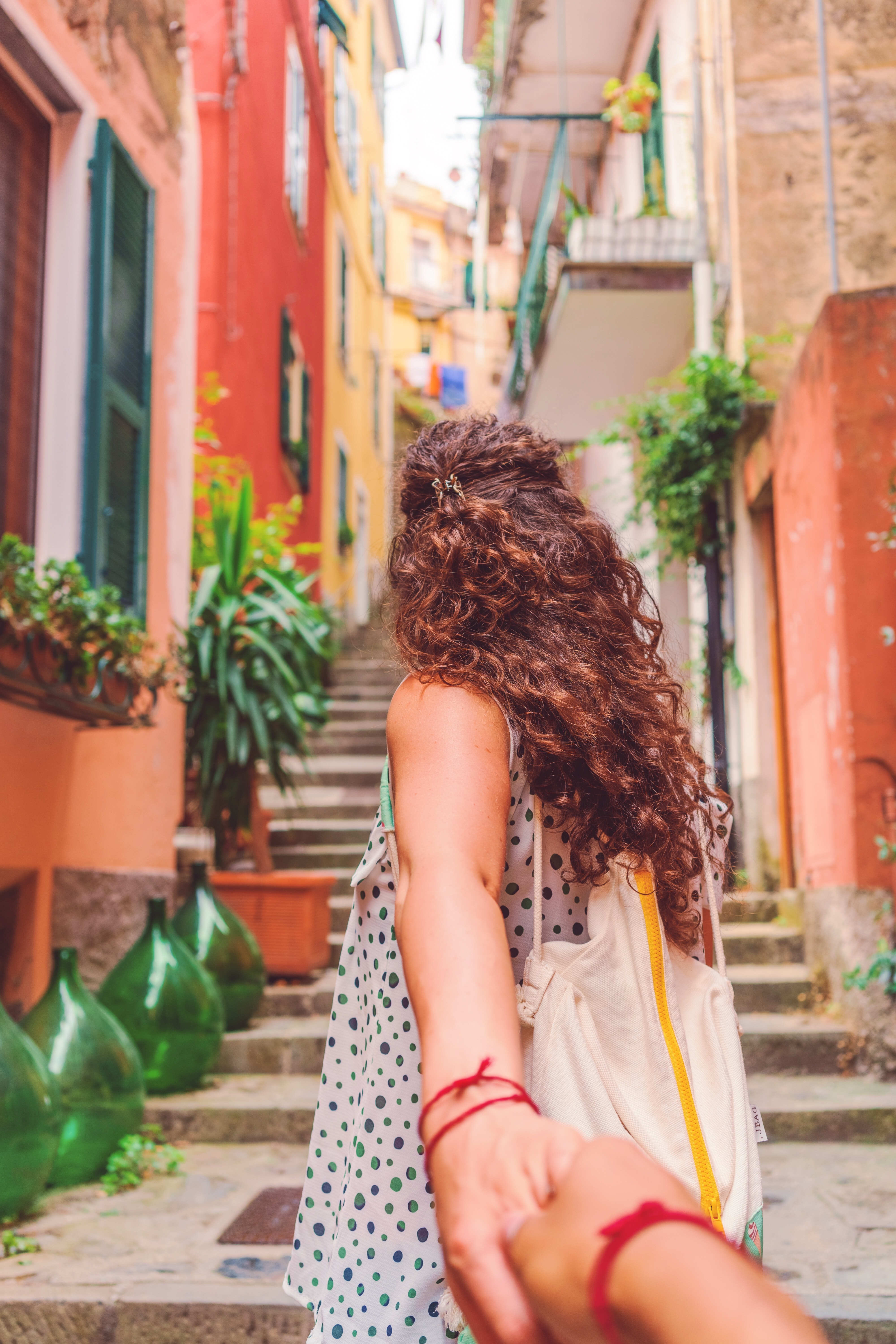 A woman rides a bicycle on a narrow street in a village in Italy