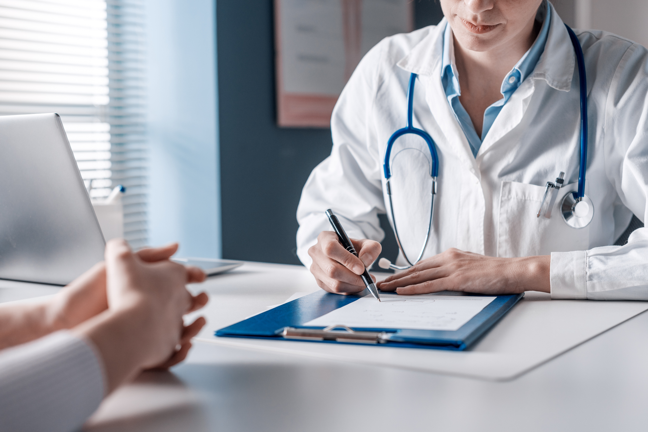 A doctor writes a prescription to one of her patients