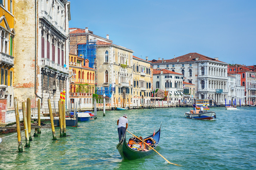 A gondolier guides a gondola through the calle of Venice