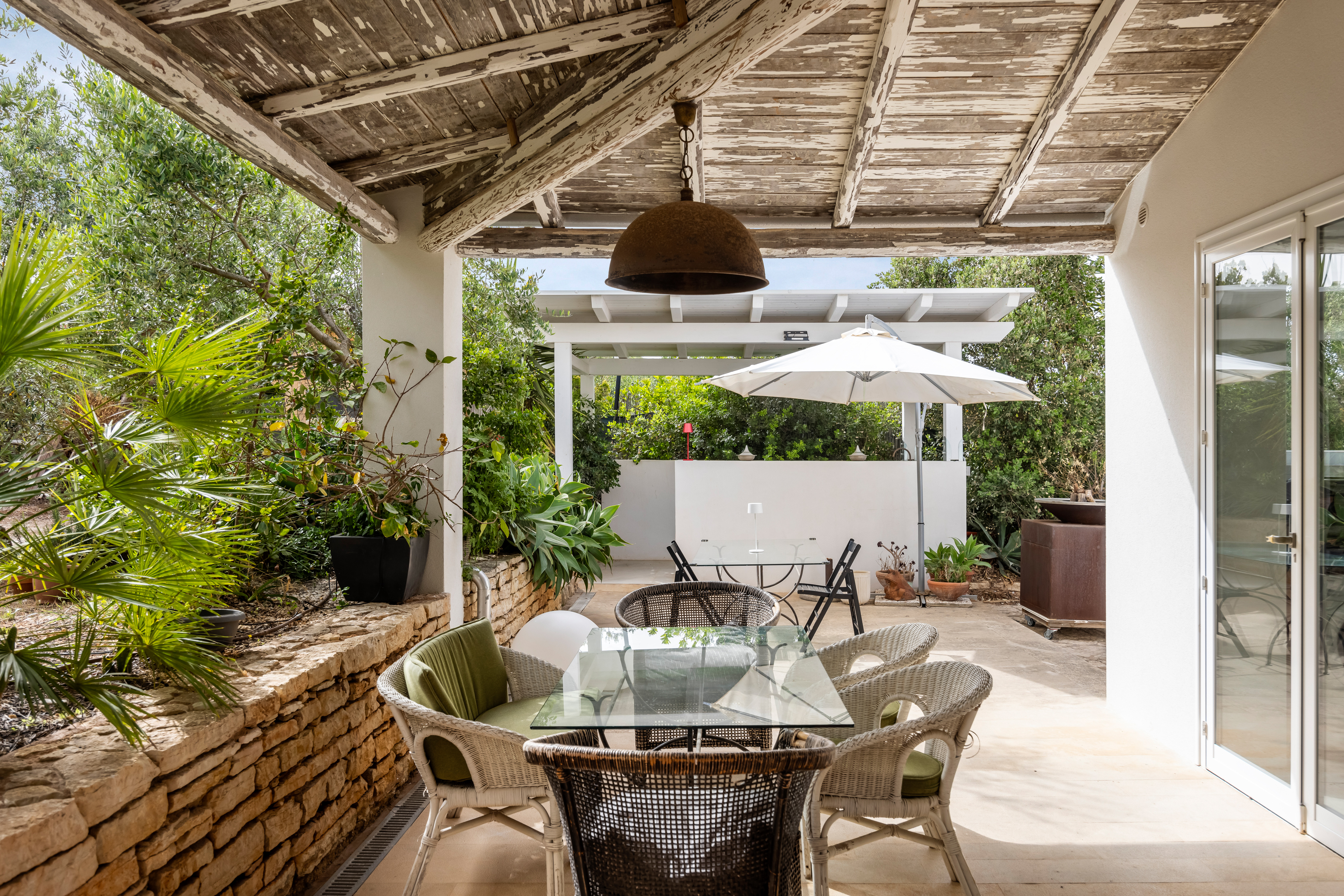 Patio esterno con tavolo, sedie e ombrellone di una villa in Sicilia