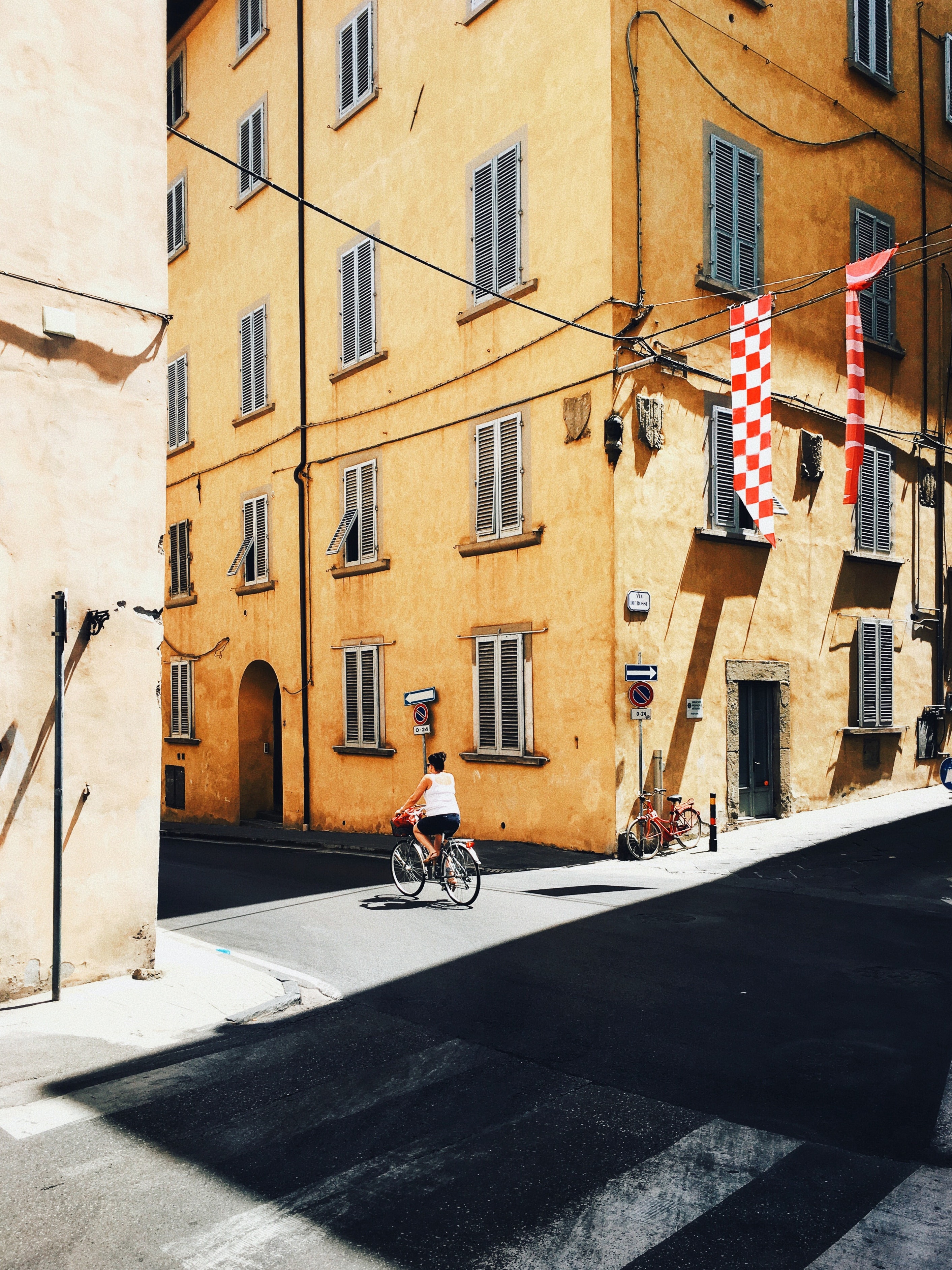 A woman rides a bicycle on a narrow street in a village in Italy