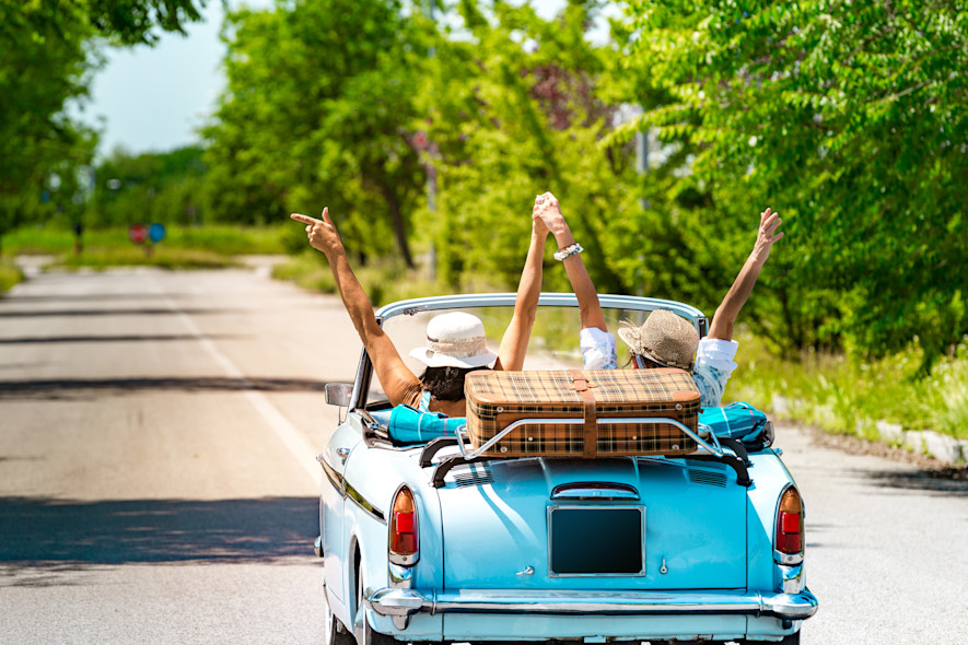 Two friends rejoice driving a vintage car during a trip to Italy