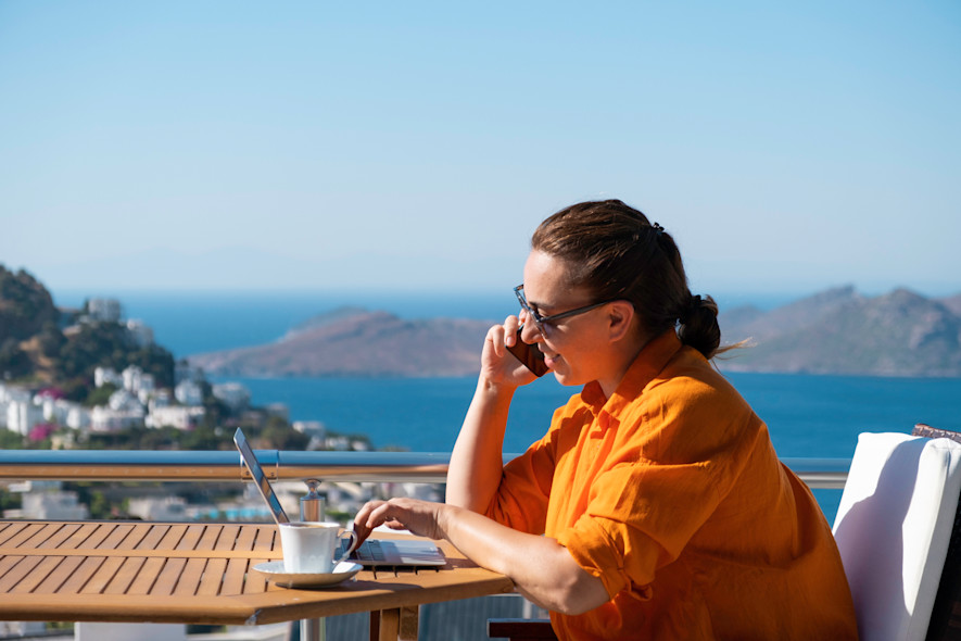 A woman works remotely on the terrace of a Wonderful Italy home overlooking the sea