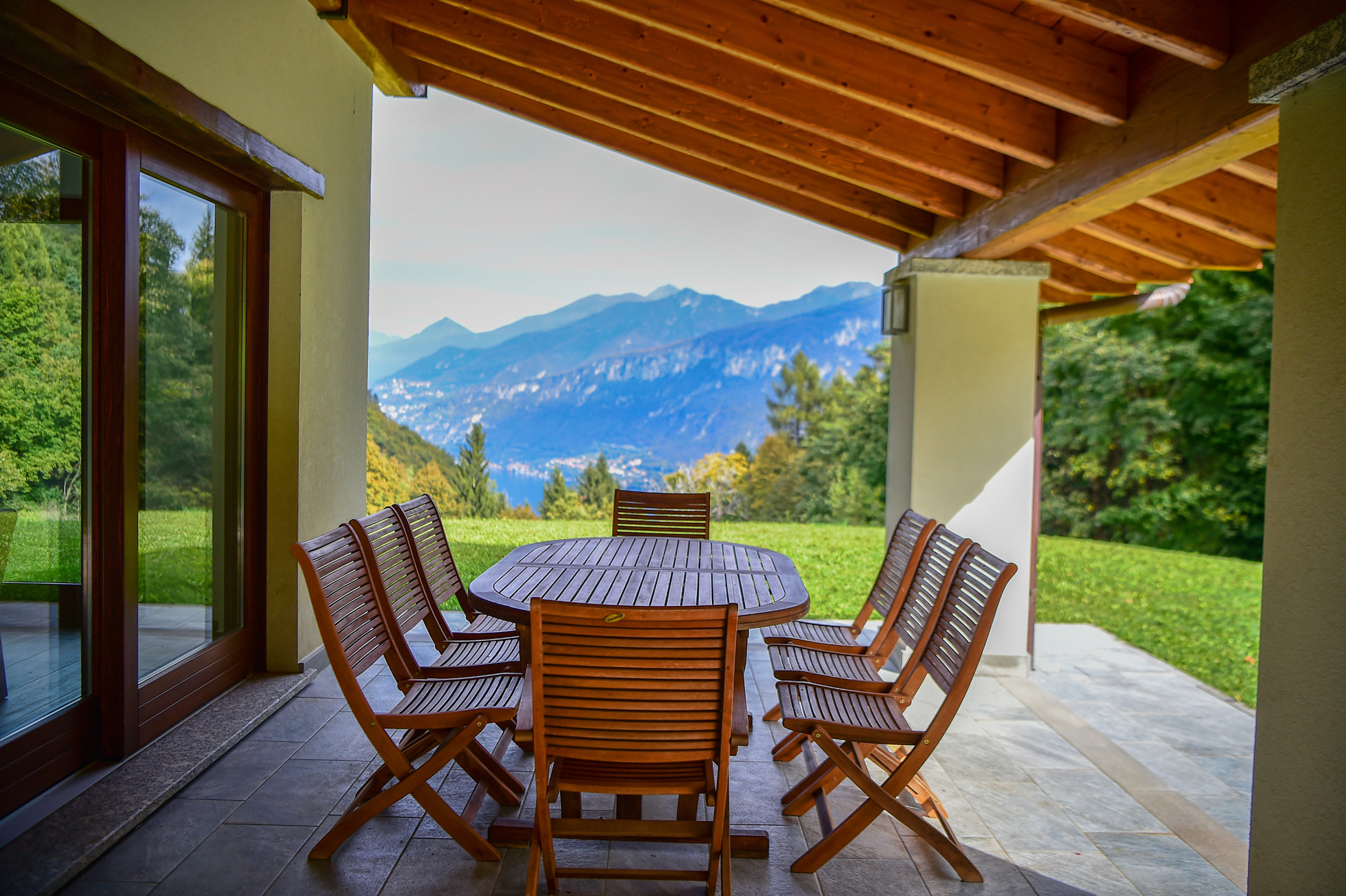 The patio with chairs and table of a villa overlooking Lake Como and the surrounding mountains