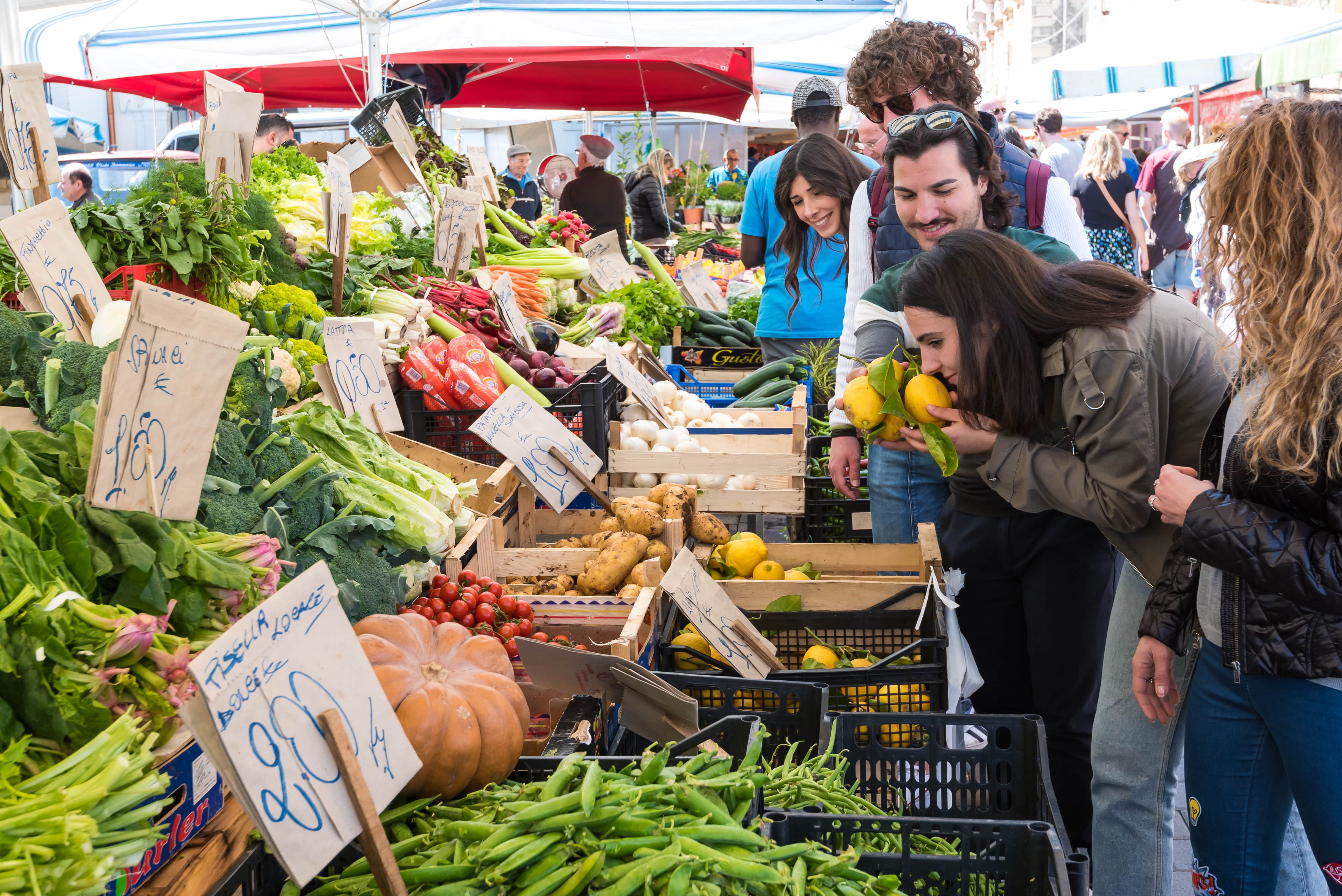 People at Ortigia market smelling the scent of Sicilian lemons