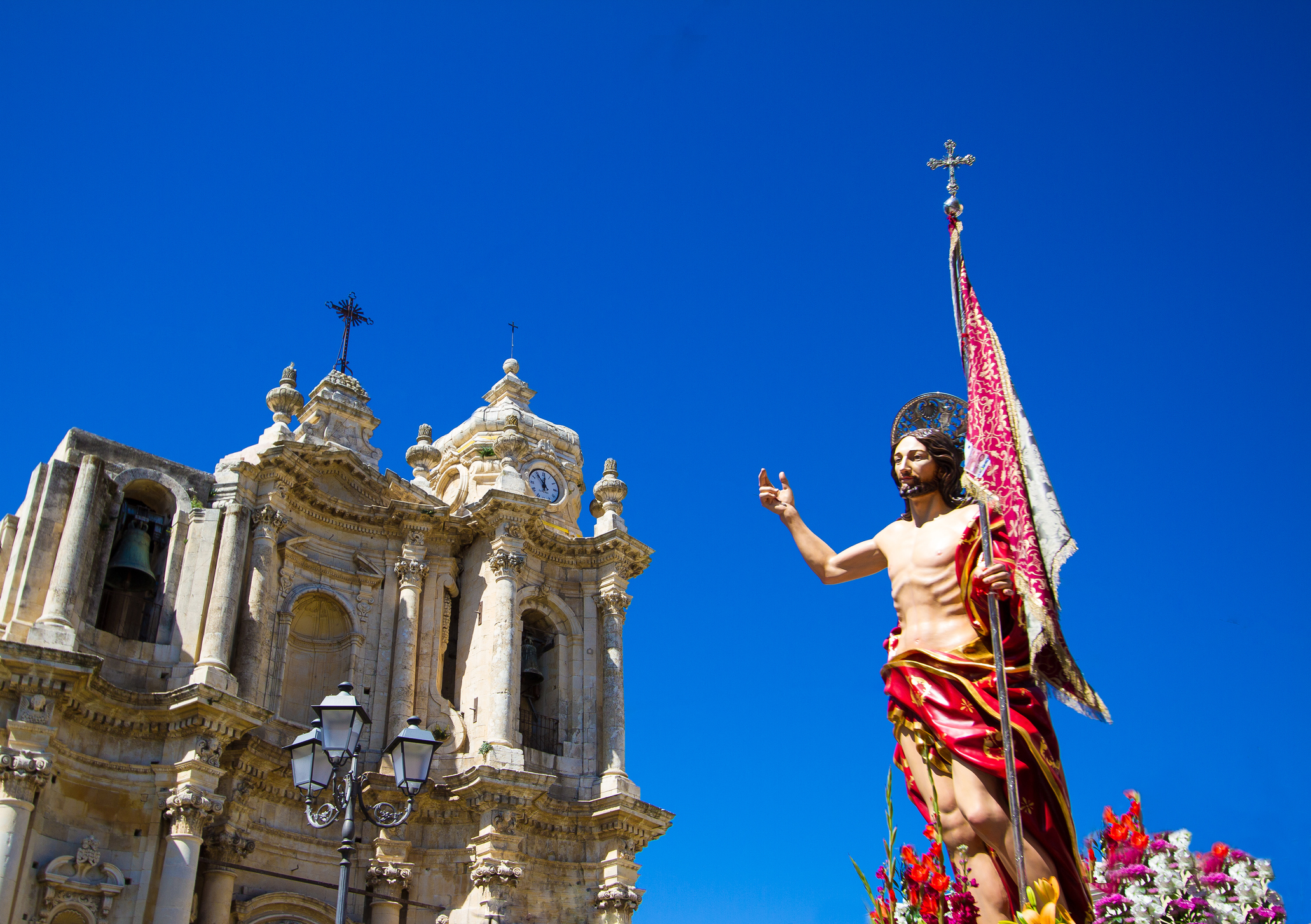 The celebration of Easter with a statue of Christ in the foreground and the Cathedral of Syracuse in the background