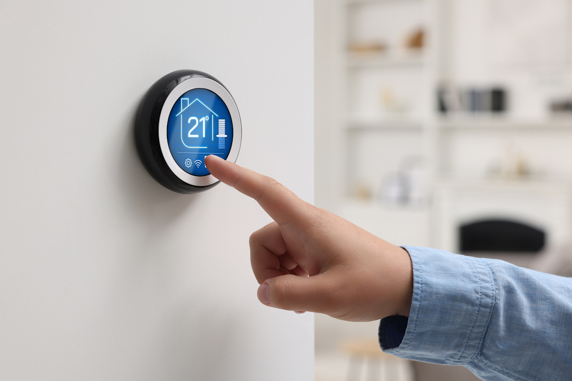 A person using a smart thermostat in their home