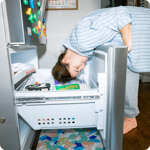 Photograph of a woman trying to cool down by sticking her head in the freezer