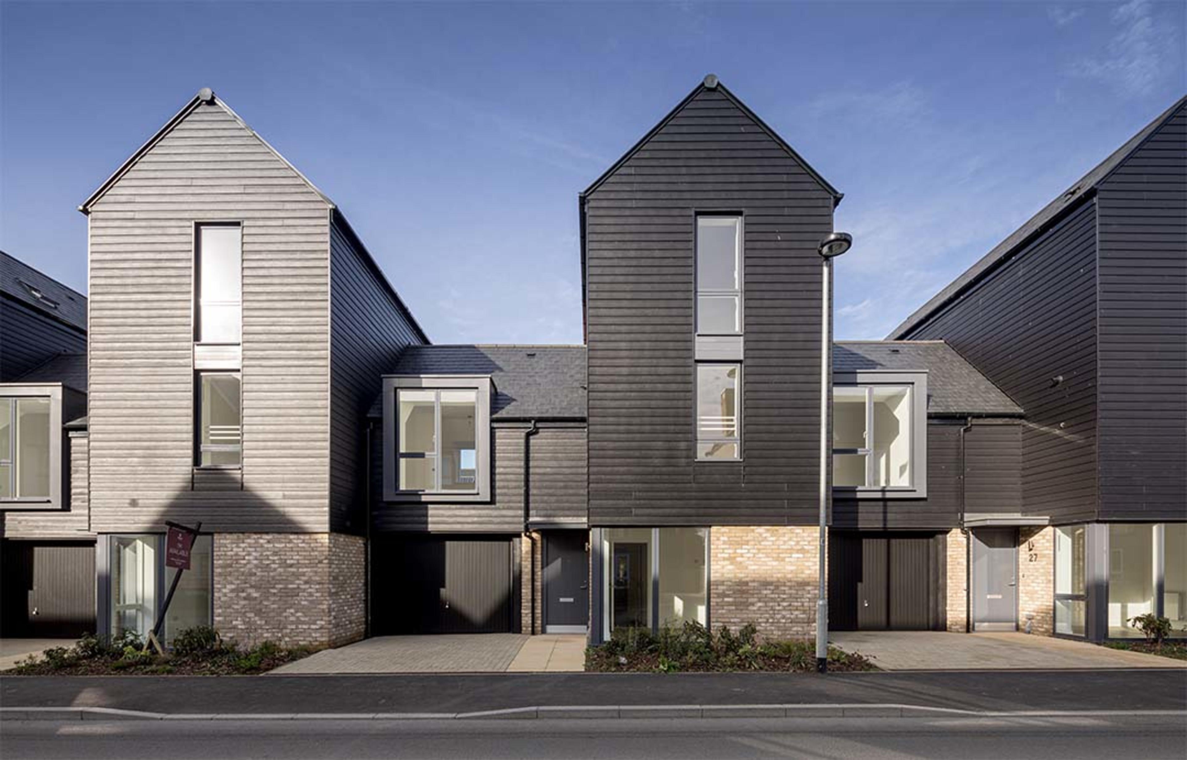 Two link detached homes with grey frontage, tall windows and driveways