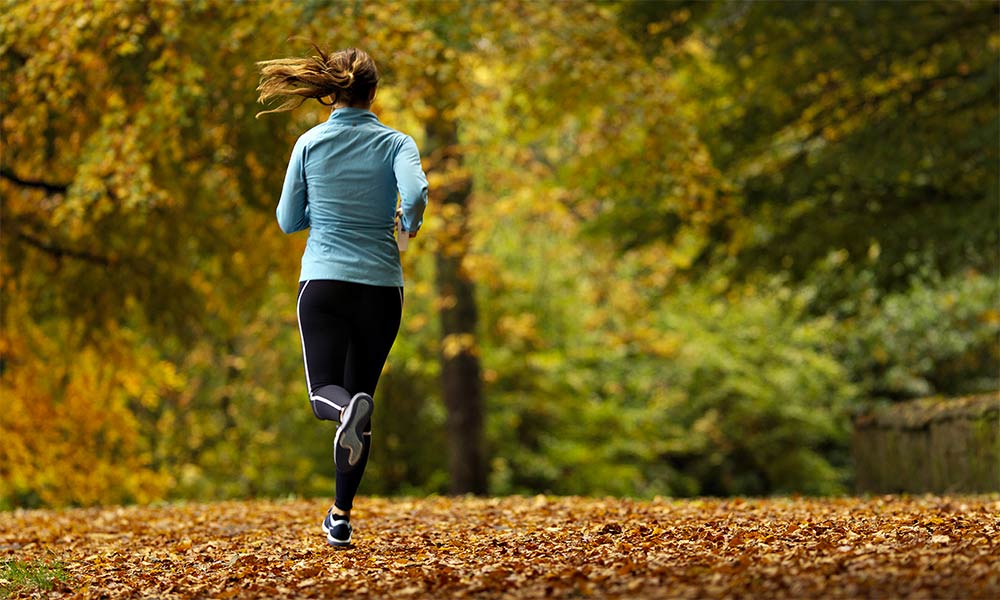 Woman jogging through a leafy park