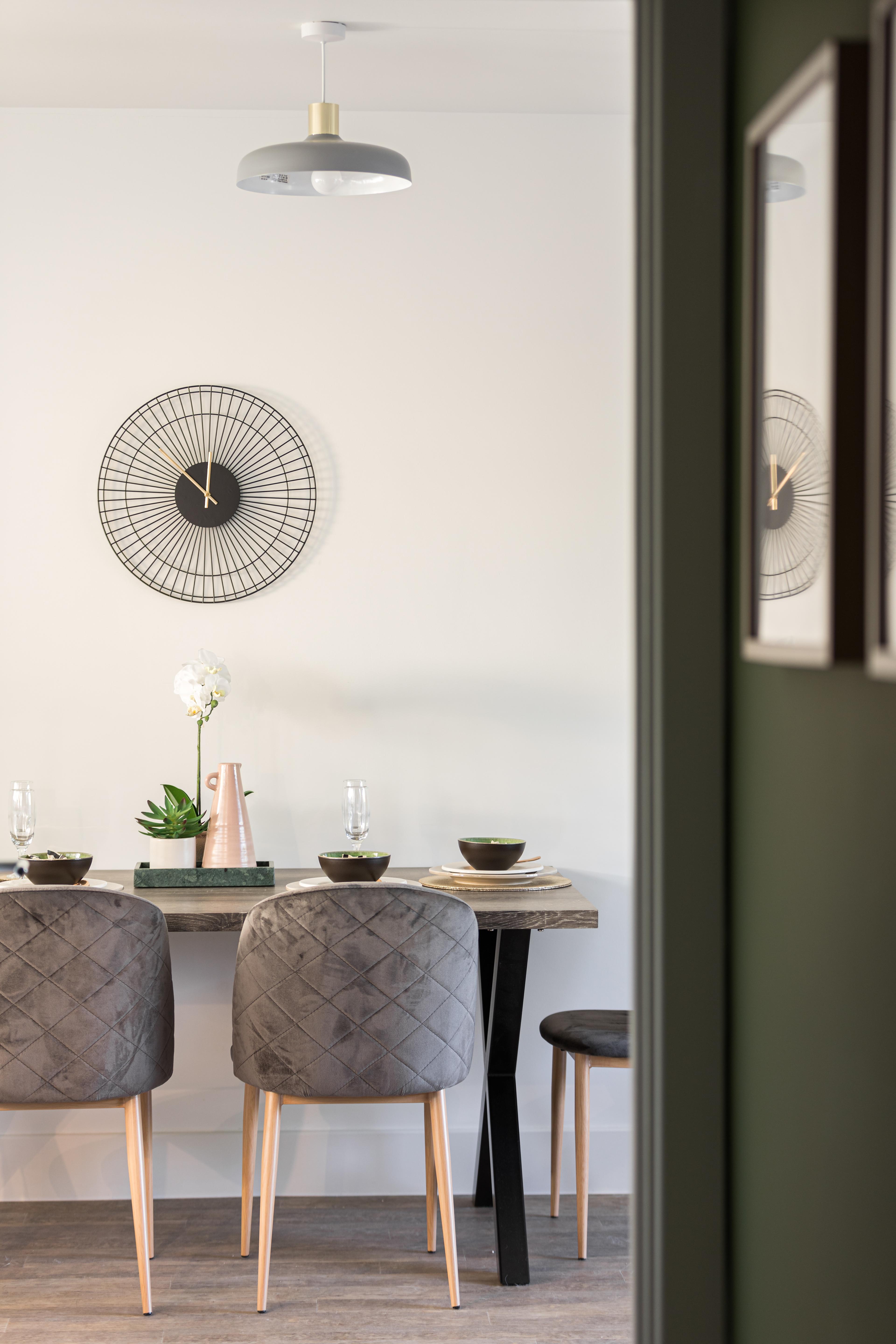 Dining table with two chairs and clock above it