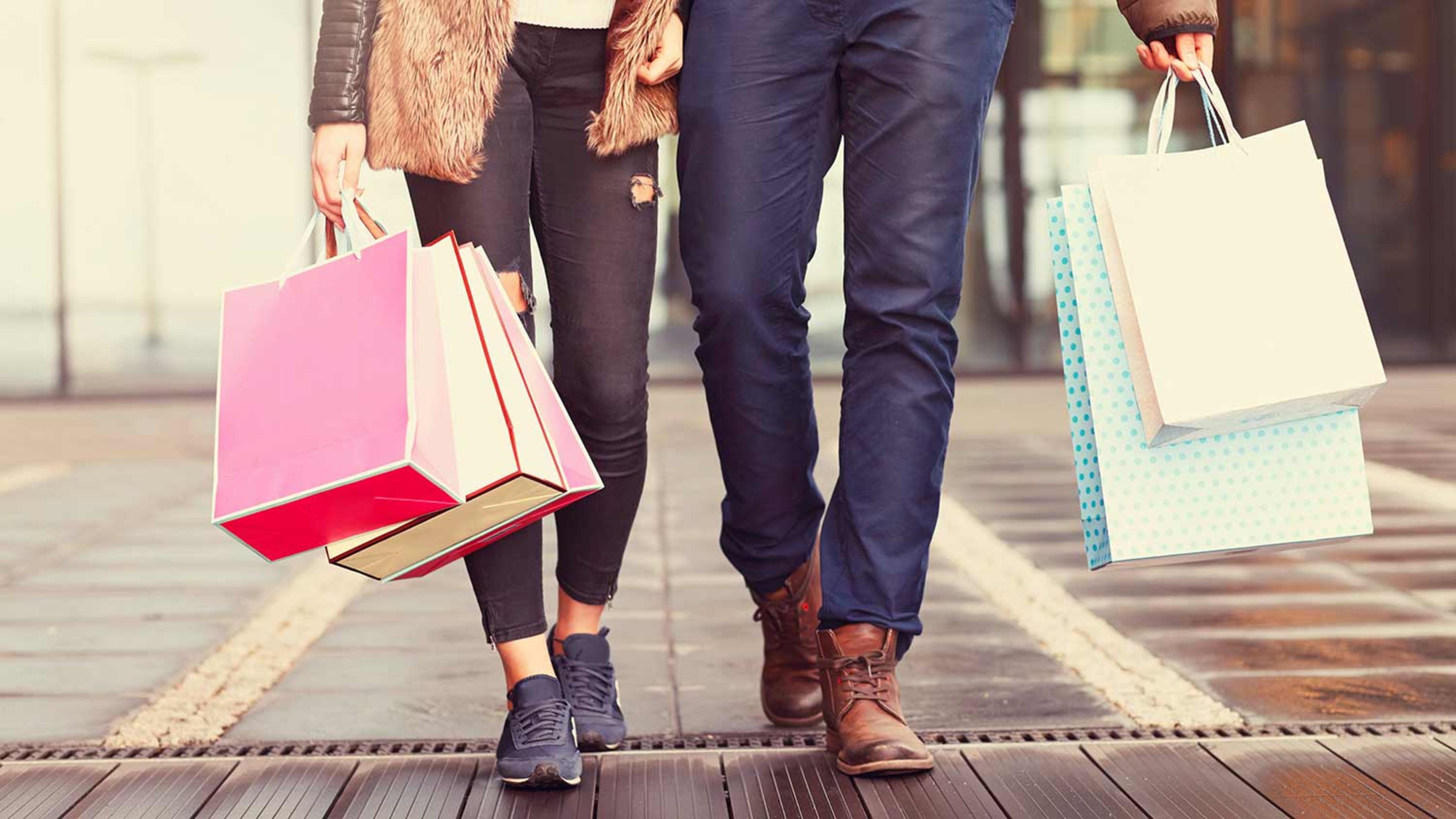 Couple walking along street holding shopping bags