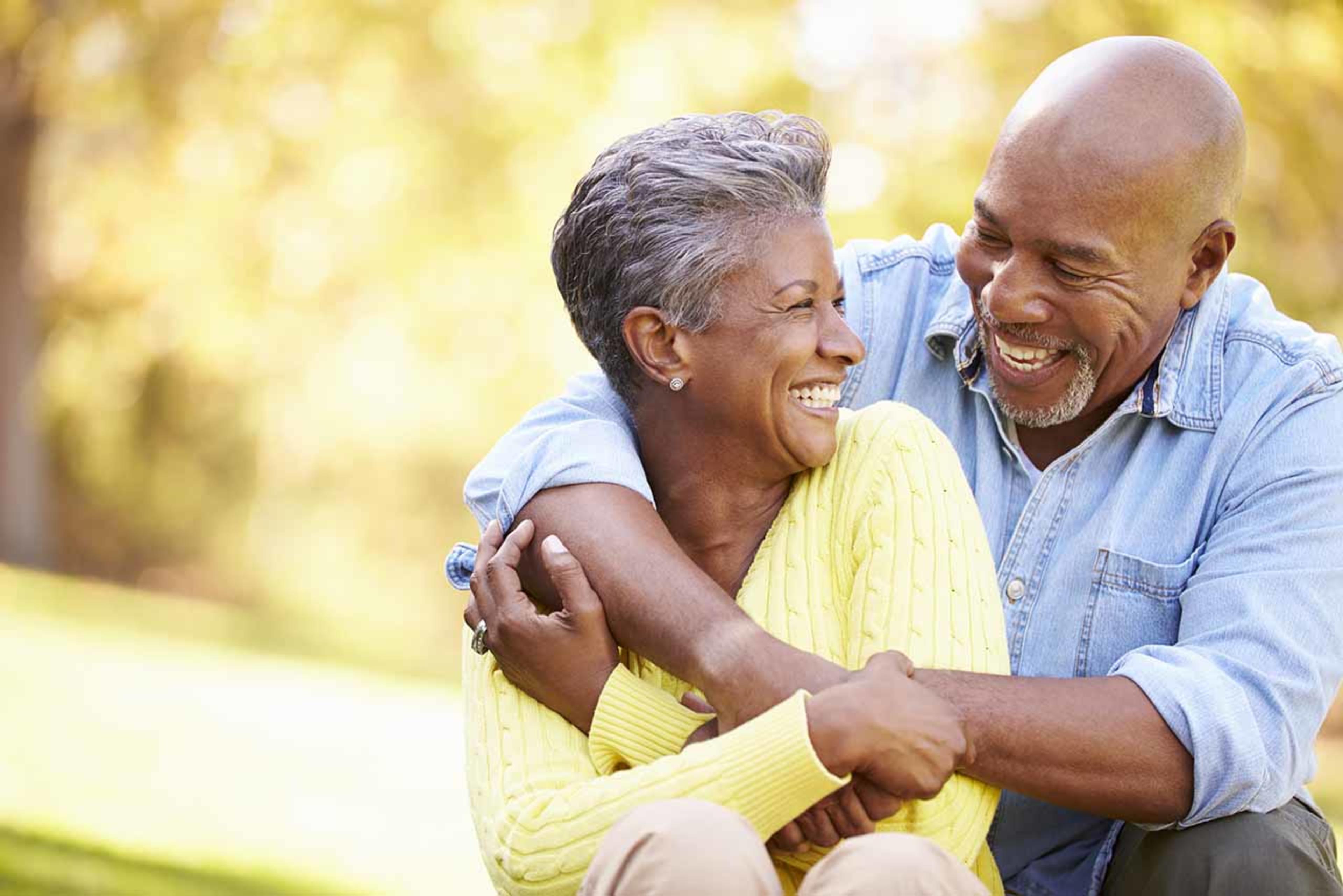 Senior couple smiling and hugging in sunlit outdoors