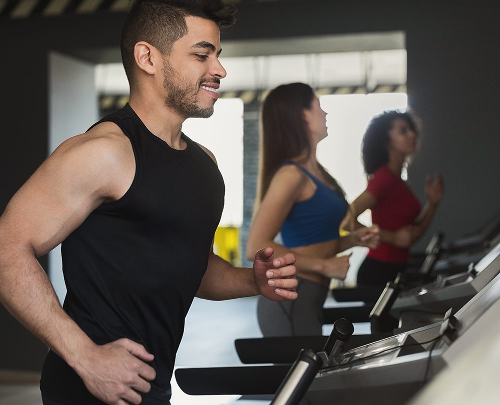 image of man running in the foreground and 2 women running in the background at the gym