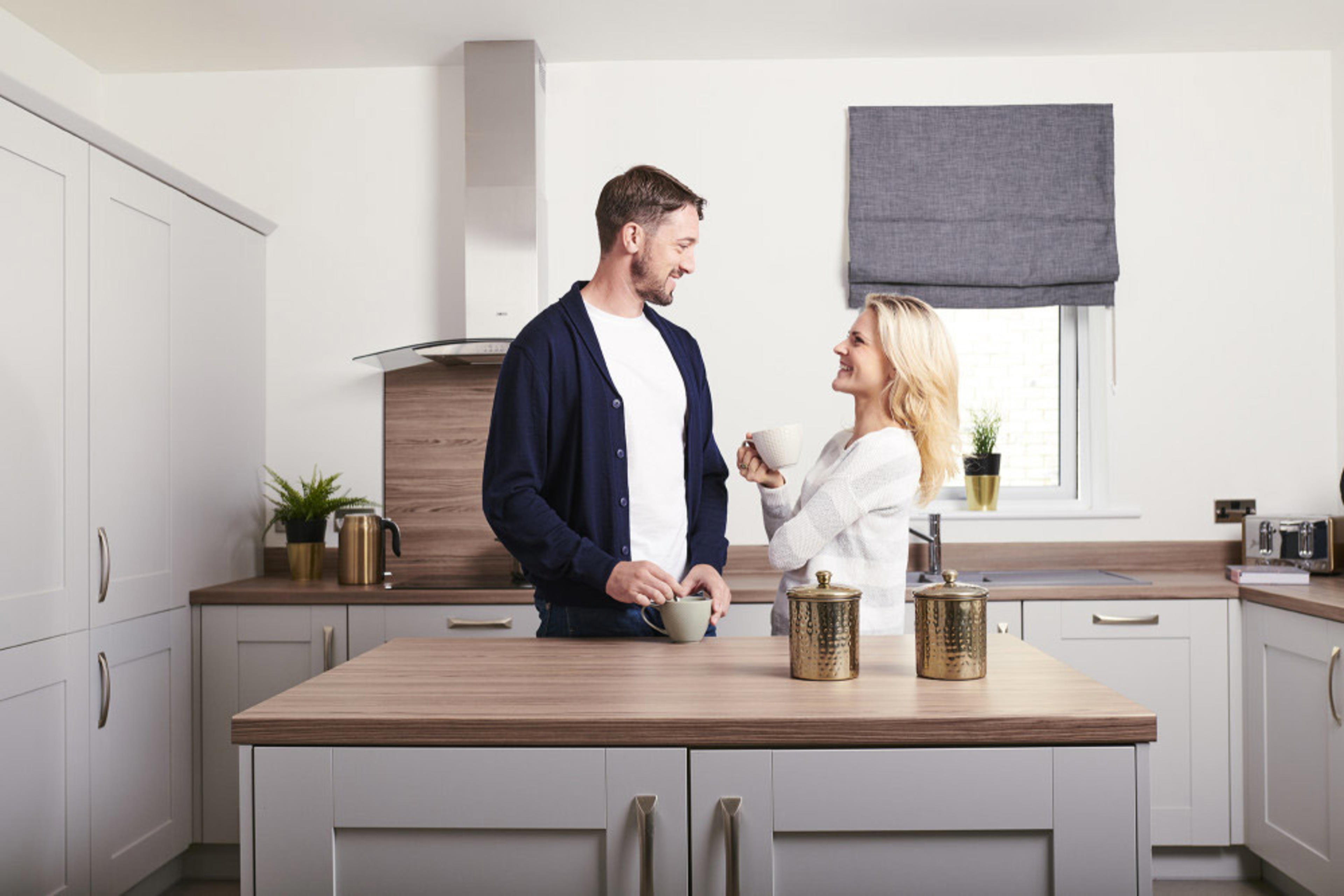 Man and Woman standing drinking coffee at kitchen island