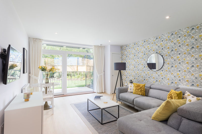 A living room with sliding patio doors, grey sofas and yellow cushions